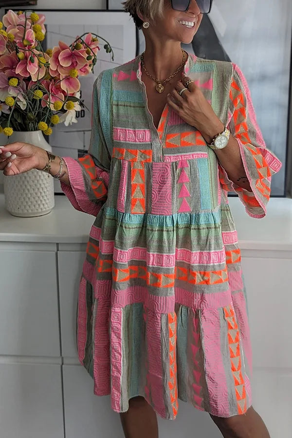 A woman wearing a boho-style mini dress with ruffles, standing outdoors in a natural setting. 2