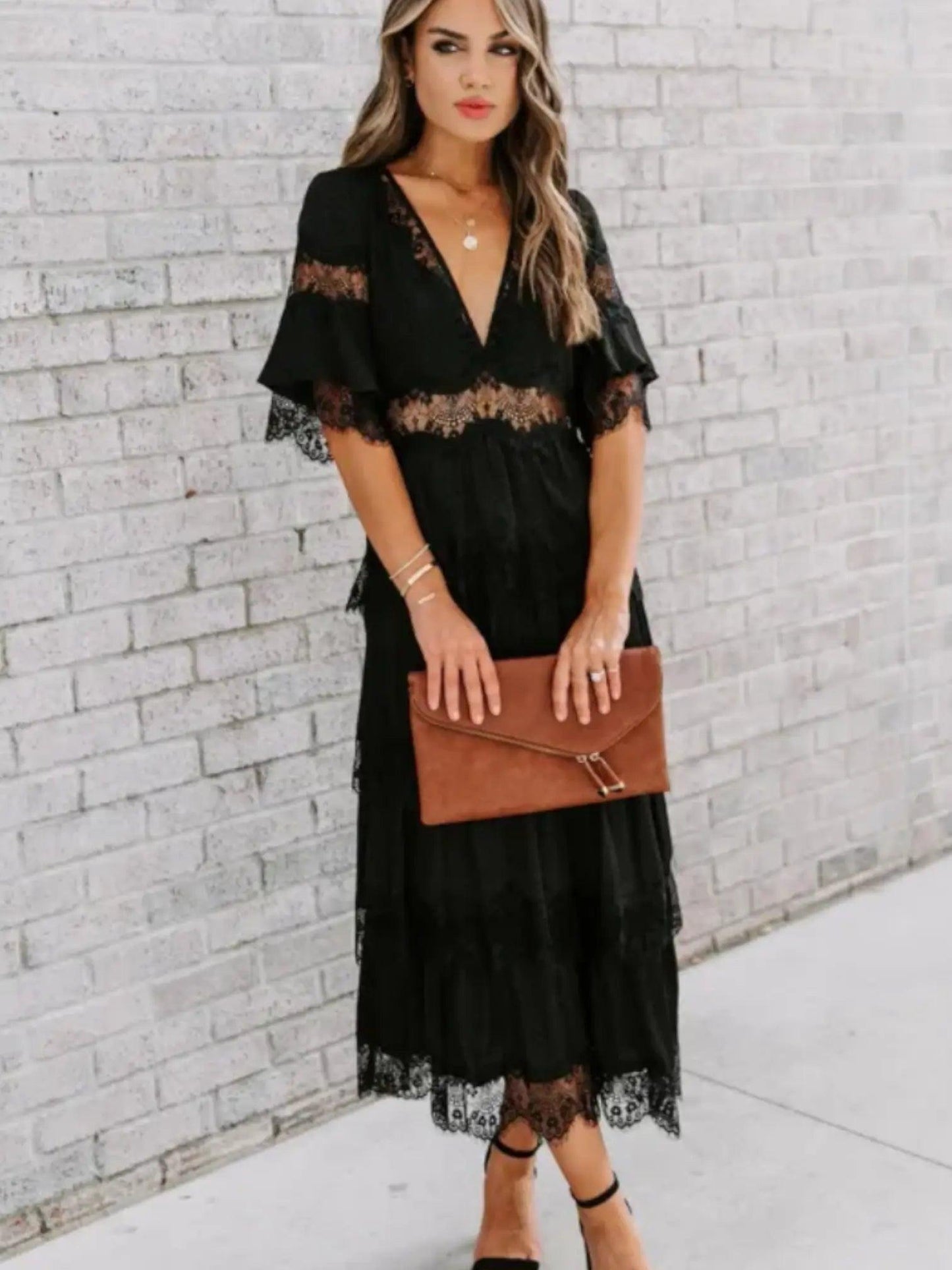 A woman wearing a long, lace maxi dress with a V-neckline and short sleeves, standing outdoors at a wedding event. 3