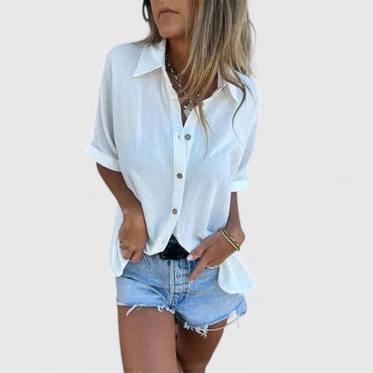 Loose-fitting women's white short-sleeve blouse displayed on a mannequin, featuring a simple design and relaxed silhouette. 0