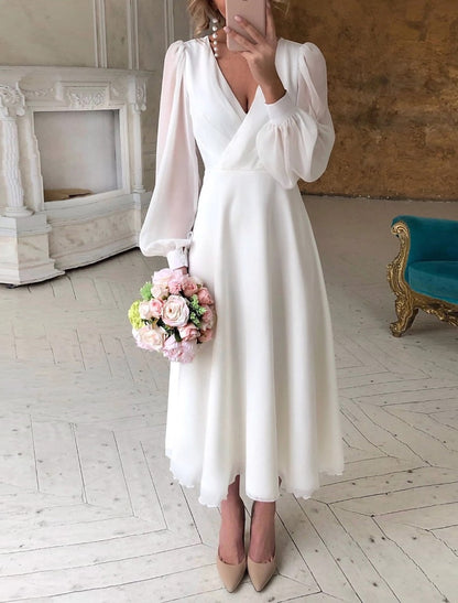 Dresses a classic, flowing wedding dress with long sleeves and a V-shaped neckline displayed on a mannequin. 0