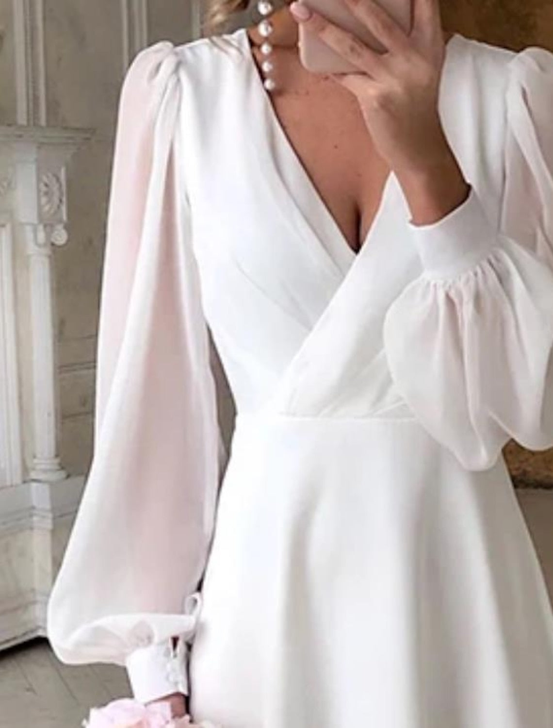 Dresses a classic, flowing wedding dress with long sleeves and a V-shaped neckline displayed on a mannequin. 1