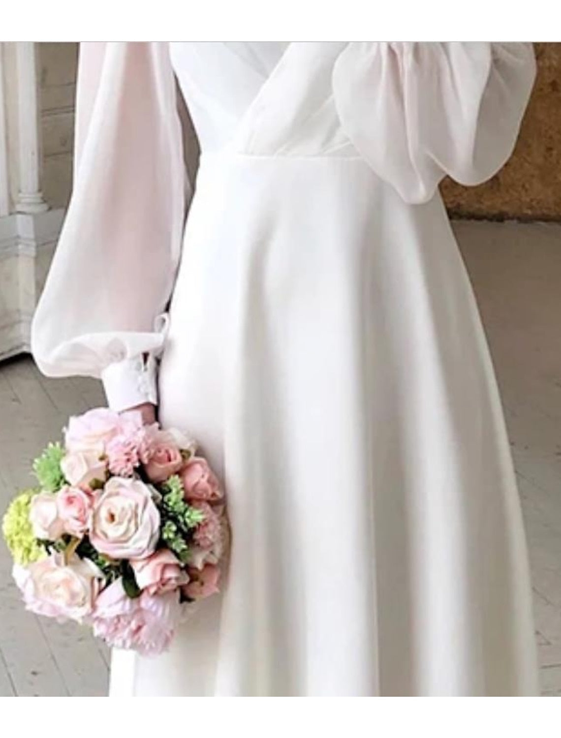 Dresses a classic, flowing wedding dress with long sleeves and a V-shaped neckline displayed on a mannequin. 2