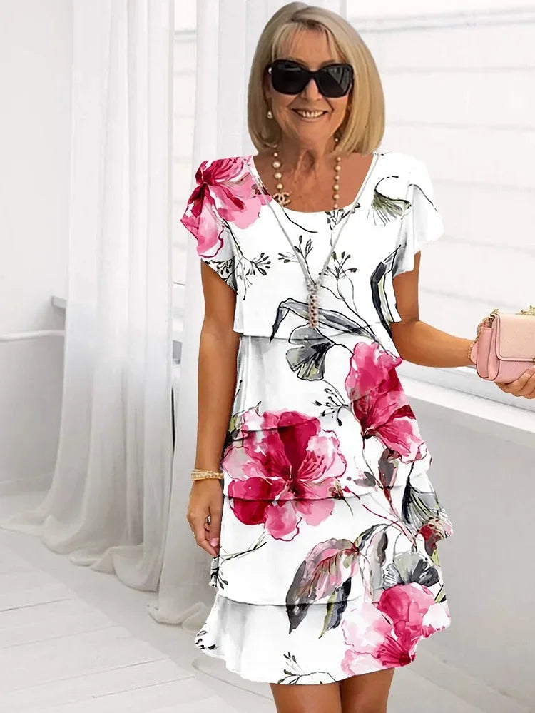 A pleated women's dress featuring a floral pattern, showcasing a flowing design with a fitted bodice and a knee-length skirt. 0