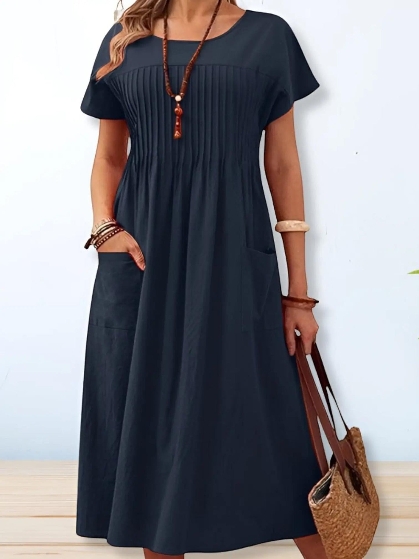 A midi dress with a loose fit and short sleeves, displayed on a mannequin. The dress has a simple, elegant design suitable for various occasions. 0