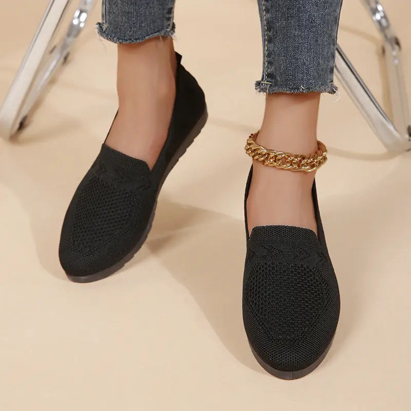 A pair of women's slip-on sneakers featuring a breathable upper design and a lightweight sole, displayed against a neutral background. 0