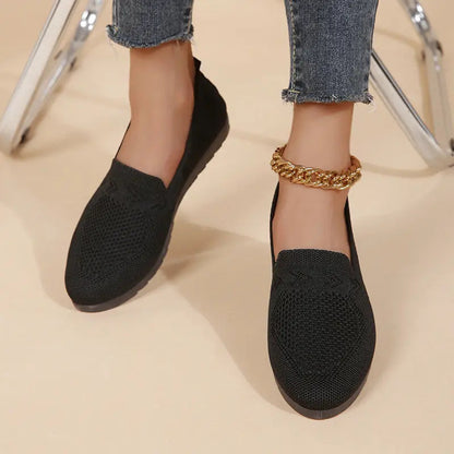 A pair of women's slip-on sneakers featuring a breathable upper design and a lightweight sole, displayed against a neutral background. 0