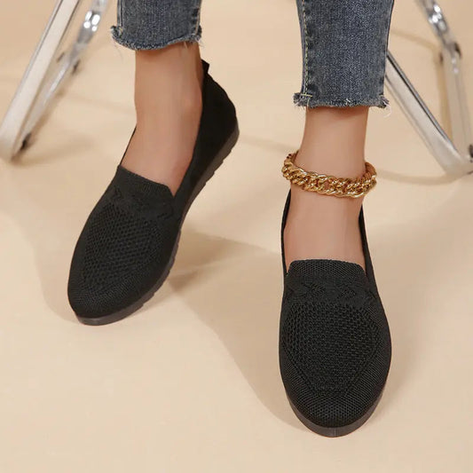 A pair of women's slip-on sneakers featuring a breathable upper design and a lightweight sole, displayed against a neutral background. 0