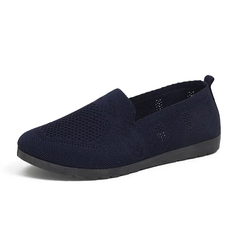 A pair of women's slip-on sneakers featuring a breathable upper design and a lightweight sole, displayed against a neutral background. 11