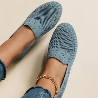 A pair of women's slip-on sneakers featuring a breathable upper design and a lightweight sole, displayed against a neutral background. 2