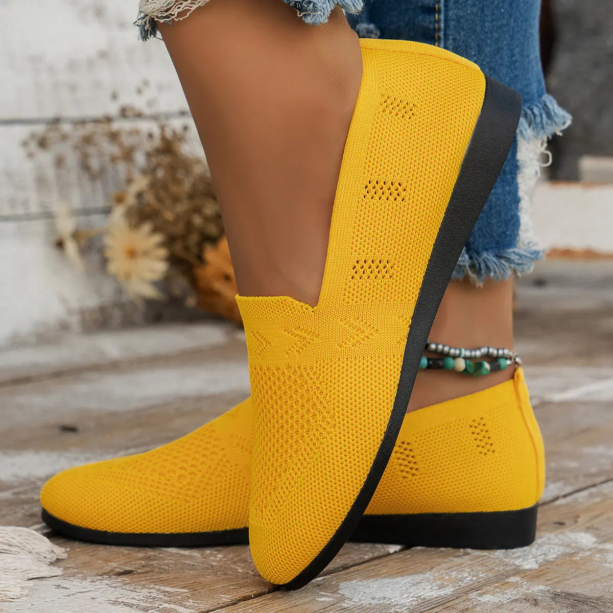 A pair of women's slip-on sneakers featuring a breathable upper design and a lightweight sole, displayed against a neutral background. 5