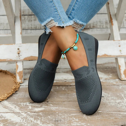 A pair of women's slip-on sneakers featuring a breathable upper design and a lightweight sole, displayed against a neutral background. 7