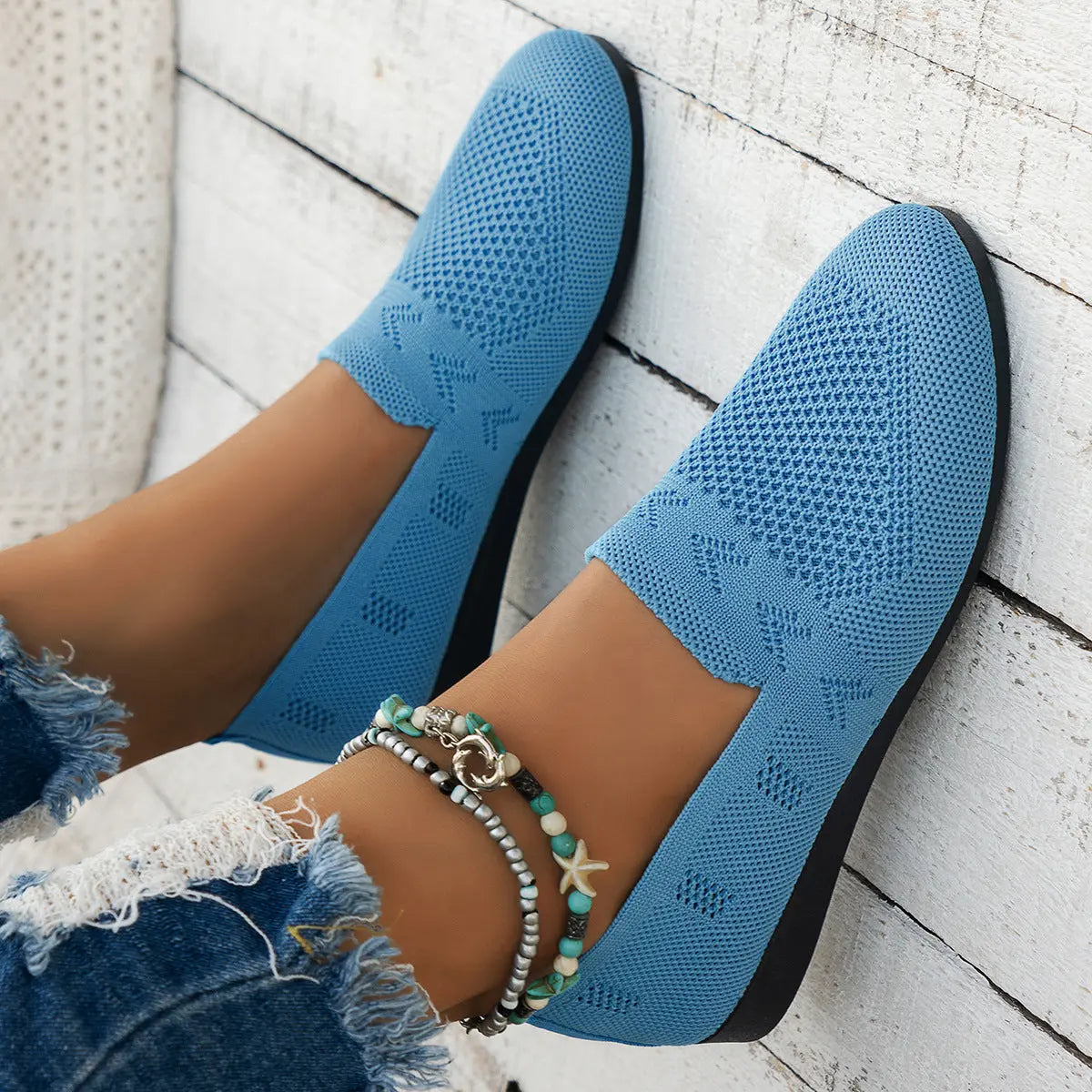 A pair of women's slip-on sneakers featuring a breathable upper design and a lightweight sole, displayed against a neutral background. 9
