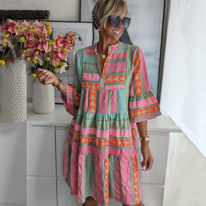 A woman wearing a boho-style mini dress with ruffles, standing outdoors in a natural setting. 0