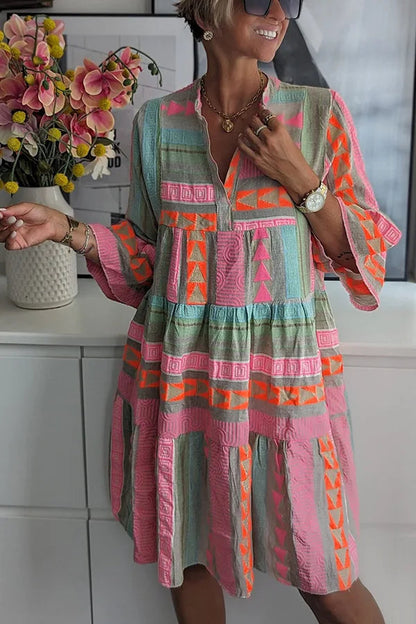 A woman wearing a boho-style mini dress with ruffles, standing outdoors in a natural setting. 2