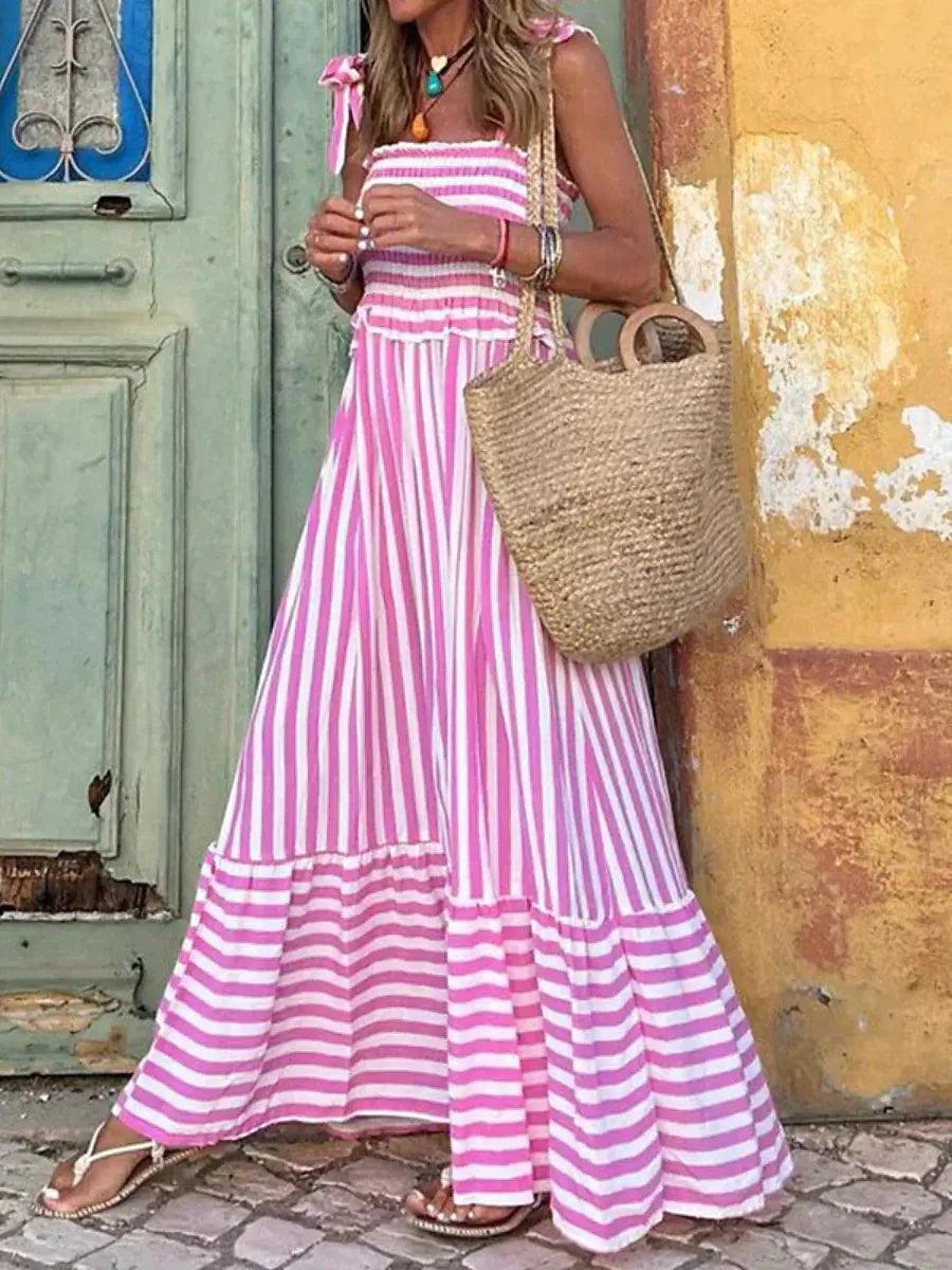 Maxi dress with a flowing silhouette and striped pattern, designed for weddings or summer outings, displayed on a hanger. 1